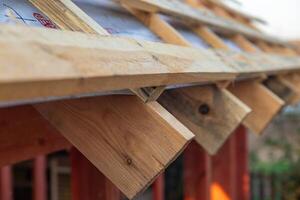 lose-up of a wooden roof frame during construction. The wooden planks are arranged in a grid pattern and supported by beams, creating a sturdy foundation for the roof. photo