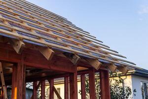 lose-up of a wooden roof frame during construction. The wooden planks are arranged in a grid pattern and supported by beams, creating a sturdy foundation for the roof. photo