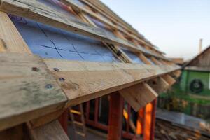 lose-up of a wooden roof frame during construction. The wooden planks are arranged in a grid pattern and supported by beams, creating a sturdy foundation for the roof. photo