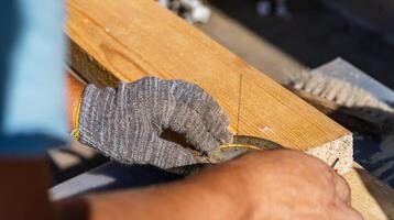 Yellow ruler placed on a wooden beam. Tools are being used to measure and mark the wooden beam for cutting or construction. The close-up view of the tools and the wooden beam. photo