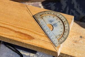 Yellow ruler placed on a wooden beam. Tools are being used to measure and mark the wooden beam for cutting or construction. The close-up view of the tools and the wooden beam. photo