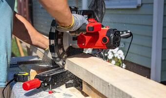 Circular saw cutting a piece of wood. The sawdust created by the saw is flying through the air. Close-up manual circular saw on slides for sawing wood in the home workshop. photo
