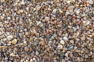 Close-up of a gravel surface. The stones are densely packed together, creating a textured and rough surface. photo