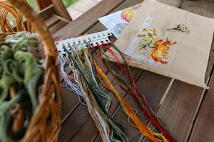 Close-up of a cross-stitch in progress. Cross-stitch with various colorful threads, a needle, and a pair of embroidery scissors. Intricate embroidery details, as well as the sewing process. photo