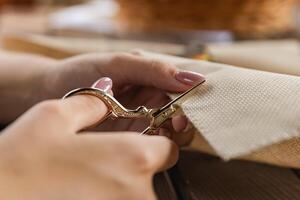 Handicraft scissors cut the fabric for cross stitch. Handicraft and creativity. Close-up of the process of cross stitching. photo