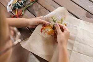 A woman doing cross stitching. Close-up of hands with a needle threading the thread through the fabric. Embroidery of a picture. In the background are colorful embroidery threads. photo