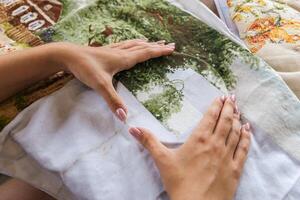 The image shows a person working on a cross-stitch embroidery project. They are using an embroidery hoop to hold the fabric taut and are carefully guiding the needle through the cloth. Hobbies. photo