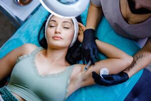 Woman Receiving Cosmetic Injections in Armpit at Beauty Salon photo