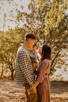 Happy family walking on the road in the park. Father, mother holding baby son on hands and going together. Rear view. Family Ties concept. photo
