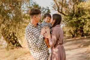 Happy family walking on the road in the park. Father, mother holding baby son on hands and going together. Rear view. Family Ties concept. photo