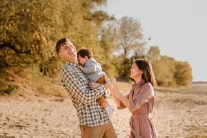 Happy family walking on the road in the park. Father, mother holding baby son on hands and going together. Rear view. Family Ties concept. photo