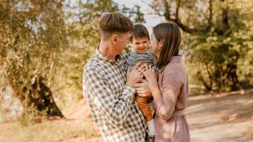 Happy family walking on the road in the park. Father, mother holding baby son on hands and going together. Rear view. Family Ties concept. photo