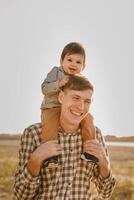 A child on his fathers neck. Walk near the water. Baby and dad against the sky photo