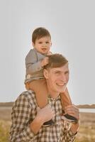 A child on his fathers neck. Walk near the water. Baby and dad against the sky photo