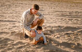 Portrait of loving father and his one years old son walking and playing with sand photo