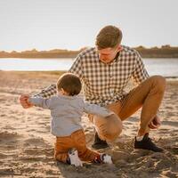 Portrait of loving father and his one years old son walking and playing with sand photo