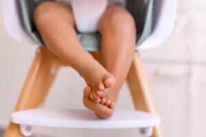 One years old child's feet on high chair while he is eating at kitchen dinner table. photo