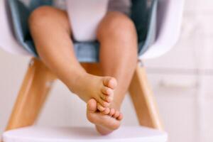 One years old child's feet on high chair while he is eating at kitchen dinner table. photo