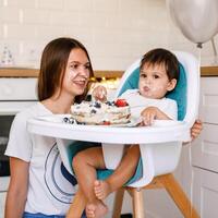 Happy mother with one year old baby celebrating with first birthday with white kitchen on background photo