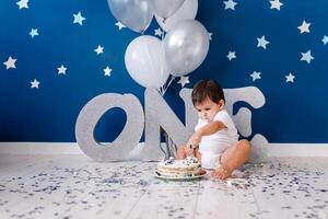 curious baby boy poking finger in his first birthday cake photo