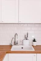 Clean white sink on wooden table in white kitchen photo