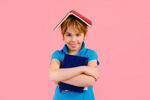 Blonde boy in t-shirt reading a book thirsty for knowledge on pink background. photo