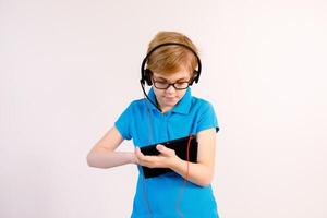 Little boy in glasses using a tablet computer with a light background photo