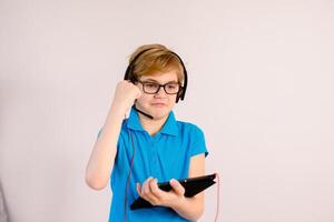 Little boy in glasses using a tablet computer with a light background photo