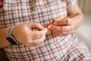 Close-up view of hands of an older woman crocheting photo