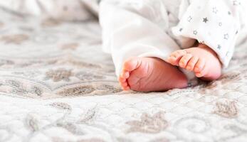 Newborn baby on a white blanket - tiny baby feet closeup photo