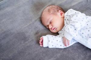 Smiling baby girl lying on a bed sleeping on blue sheets photo
