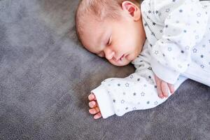 Smiling baby girl lying on a bed sleeping on blue sheets photo