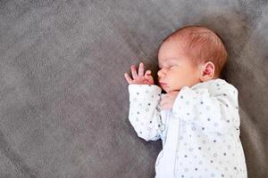 Peaceful baby lying on a bed while sleeping in a bright room. photo