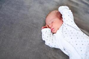Baby newborn sleeping covered on gray woolen blanket photo