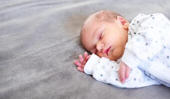 Peaceful baby lying on a bed while sleeping in a bright room. photo