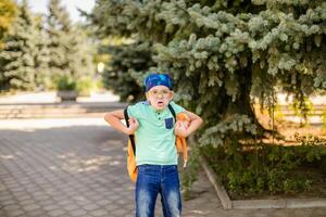 cheerful young boy with glasses and bandana, in green top and denim shorts playing with a toy monkey photo