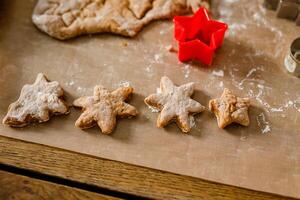 Close-up of children's hands cutting cookies with a cookie cutter on gingerbread dough photo