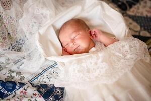 Newborn baby for the first time at home, lying in a blanket on the bed, smiling, yawning, pulling pens, falling asleep, baby's morning, baby products concept. photo