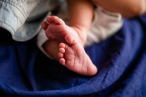 Tiny bare feet of a newborn baby in his mother's arms photo