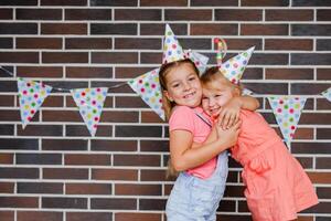 Two girls in holiday hats hugging and saying happy holidays photo