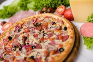 Delicious fresh Pizza with tomatoes, mashrooms, bacon and cheese mozzarella on the white wooden table. photo