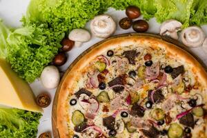High angle view of homemade pizza on wooden table surrounded by vegetables, mushrooms and cheese photo
