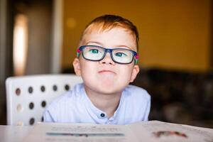 Cute toddler boy with down syndrome with big glasses reading intesting book photo