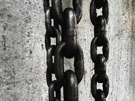 Old and rust iron chain hanging on wall, photo