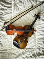 Two different size of violins and bows put on soft cotton cloth, photo