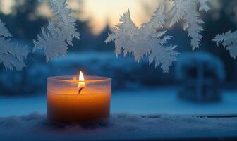 A candle is lit in a glass jar on a snowy window sill photo