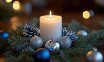 A candle is lit on a table with a pine cone and a bunch of Christmas ornaments photo