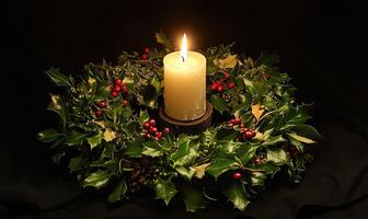 A candle is lit in a wreath of evergreen leaves photo