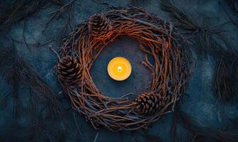A wreath of pine branches with a candle in the center photo