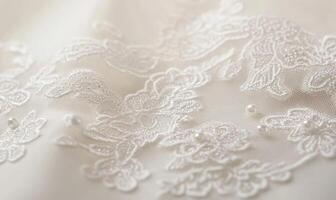 A close up of a white lace with flowers and pearls photo